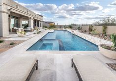 an outdoor swimming pool with lounge chairs and cactus in the foreground on a sunny day