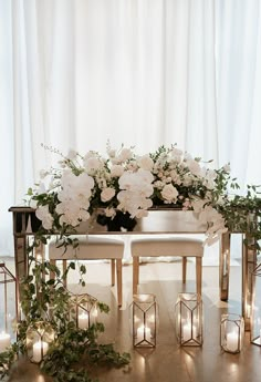 white flowers and candles sit on a table surrounded by greenery