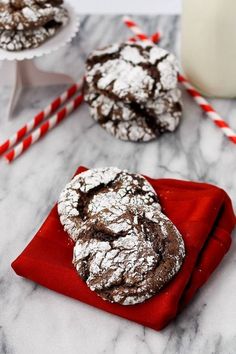 chocolate crinkle cookies sitting on top of a red napkin next to a glass of milk