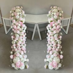 two white and pink flowers are arranged in the shape of an arch on a table