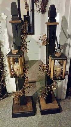 two black and gold lanterns are sitting on the floor in front of a white wall