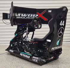 the front end of a race car sitting on top of a cement floor next to a garage