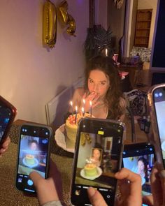 several people holding up their cell phones to take pictures with candles in the cake on them