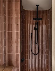 a bathroom with brown tiles and a black shower head