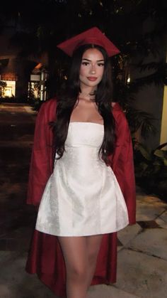 a woman in a white dress and red graduation cap