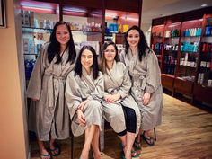 four women in robes are sitting on a chair