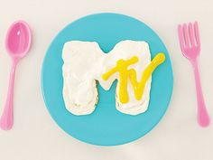 a blue plate topped with white frosting next to pink and yellow utensils