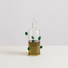 a bottle filled with liquid sitting on top of a white table next to a green object