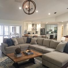 a living room filled with lots of furniture and a chandelier hanging from the ceiling