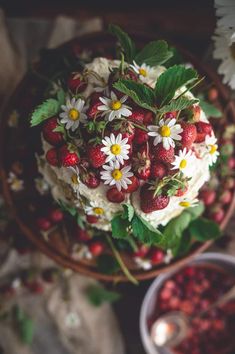 strawberries and daisies on top of a cake