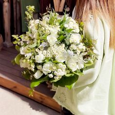 a woman holding a bouquet of white flowers