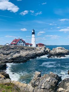 a light house sitting on top of a rocky cliff next to the ocean with waves crashing in front of it