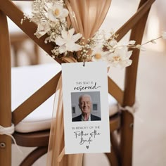 a card attached to the back of a wooden chair with flowers and ribbon around it