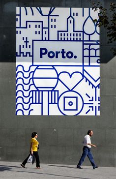 two people walking past a large advertisement on the side of a building