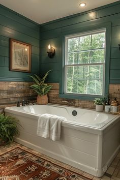 a bath tub sitting under a window next to a rug and potted plant in front of it