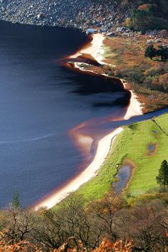 an aerial view of a body of water surrounded by land and trees in the foreground