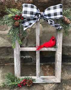 a red cardinal sitting on top of a wooden window frame with pine cones and berries