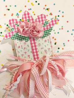 this precious cake topper is decorated with pink flowers and ribbons, which are attached to a gift box