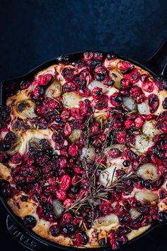 a cranberry and rosemary pizza in a cast iron skillet on a black surface