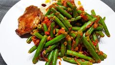 a white plate topped with green beans and meat