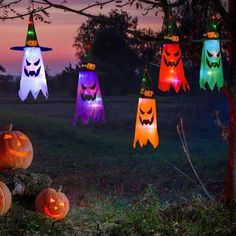 halloween lights hanging from a tree with pumpkins