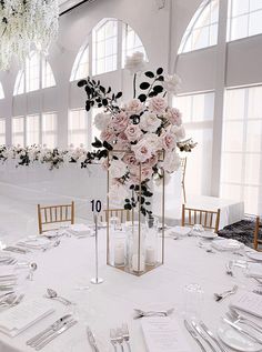 the table is set with silverware and flowers in tall vases on each side