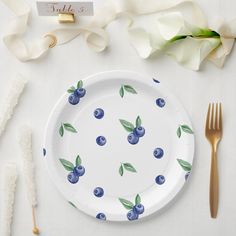 a white plate with blueberries on it next to silverware and napkins, along with calligraphy