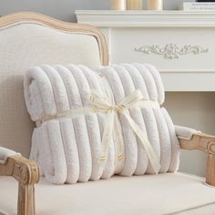 four white pillows stacked on top of each other in front of a chair with an arm rest