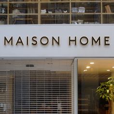 a store front with the name maison home on it's side and a plant in the window