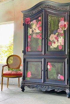 an armoire with flowers painted on it next to a chair