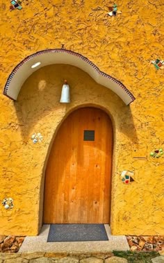 a yellow building with a wooden door and bell