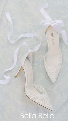 a pair of white wedding shoes sitting on top of a blue and white wallpaper