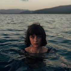 a woman floating in the water with her head above the water's surface, looking at the camera