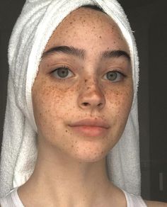 a woman with freckles on her face wearing a towel