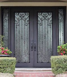 the front door to a home with two potted plants on each side and an iron gate