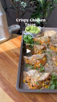 a tray filled with tacos sitting on top of a wooden table next to a plant