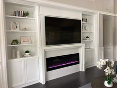 a living room with a fireplace and built - in entertainment center on the wall above it