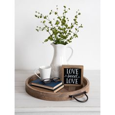 a vase with some flowers and two books on a tray next to a coffee cup