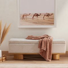 a bed with a blanket on top of it next to a potted plant and vase