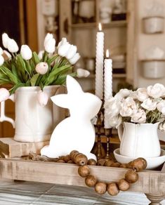 a wooden tray topped with white flowers and candles