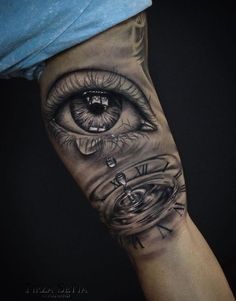 an eye tattoo on the arm with some water and clock parts in it's center