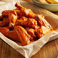 some chicken wings are in a basket on a table