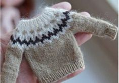 a hand holding a small knitted sweater in it's palm