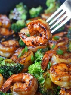 broccoli and shrimp being cooked in a skillet with a fork on top