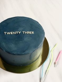 there is a blue cake with the words twenty three on it and two toothbrushes next to it