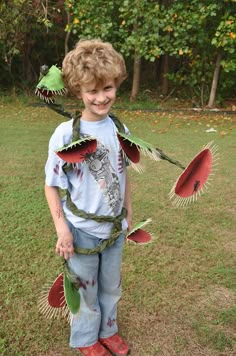 a young boy is dressed up as a scarecrow and holding two red paper plates