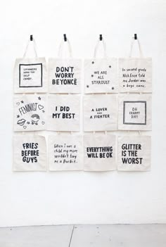 six tote bags hanging on the wall with different sayings and phrases printed on them