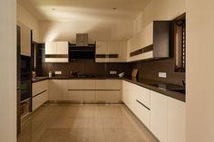 an empty kitchen with white cabinets and black counter tops, along with beige tile flooring