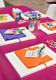 the table is set up with many different colored papers and pencils, pens and markers