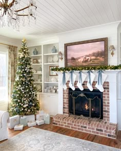 a living room decorated for christmas with a tree and stockings on the fireplace mantel